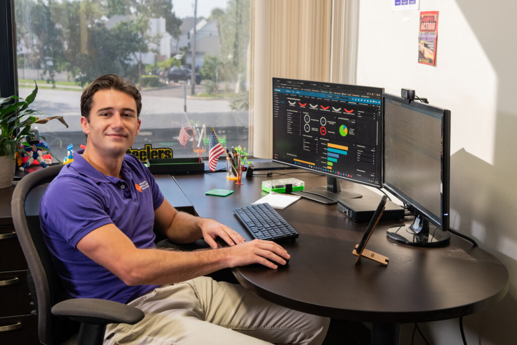 IT support technician monitoring managed services dashboards and business systems from a dual-monitor workstation in a professional office.